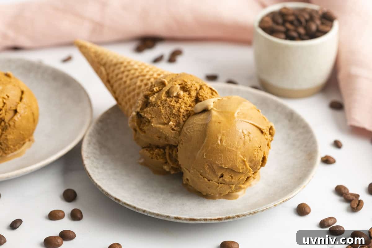 Homemade Espresso Ice Cream Recipe — Rich Coffee Gelato 7 Homemade espresso ice cream in a cone laid on a plate. Espresso coffee beans are scattered around.