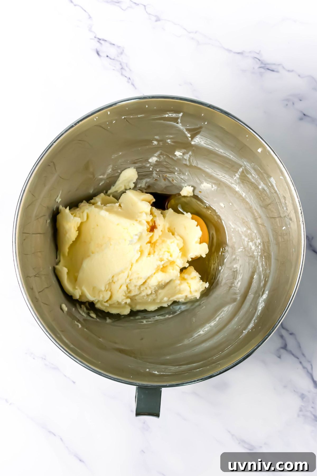 Soft dough of butter and sugars, mixed together in a silver bowl.