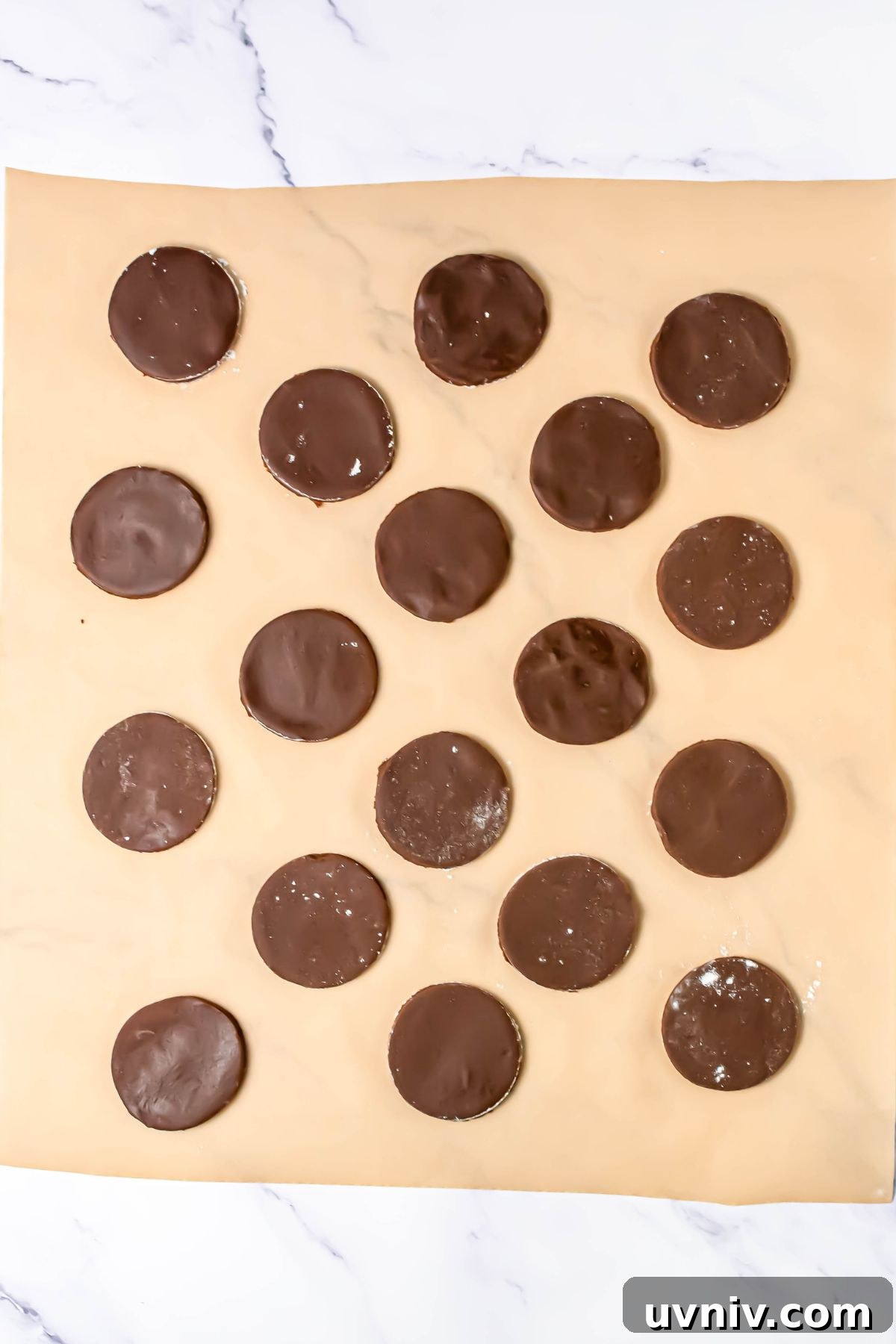 Chocolate cookies dipped in melting chocolate, then placed on parchment paper to dry.