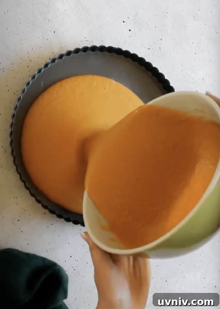 Hands pouring pumpkin filling into a skillet.