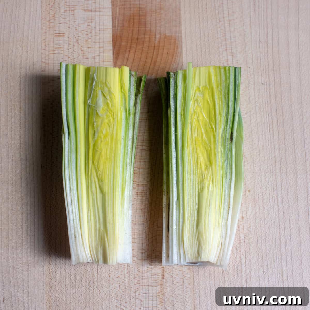 A leek sliced in half on a cutting board.