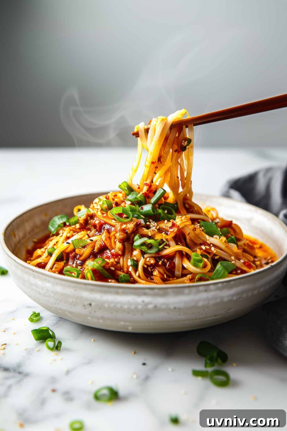 Easy szechuan noodles with green onions in a white bowl.