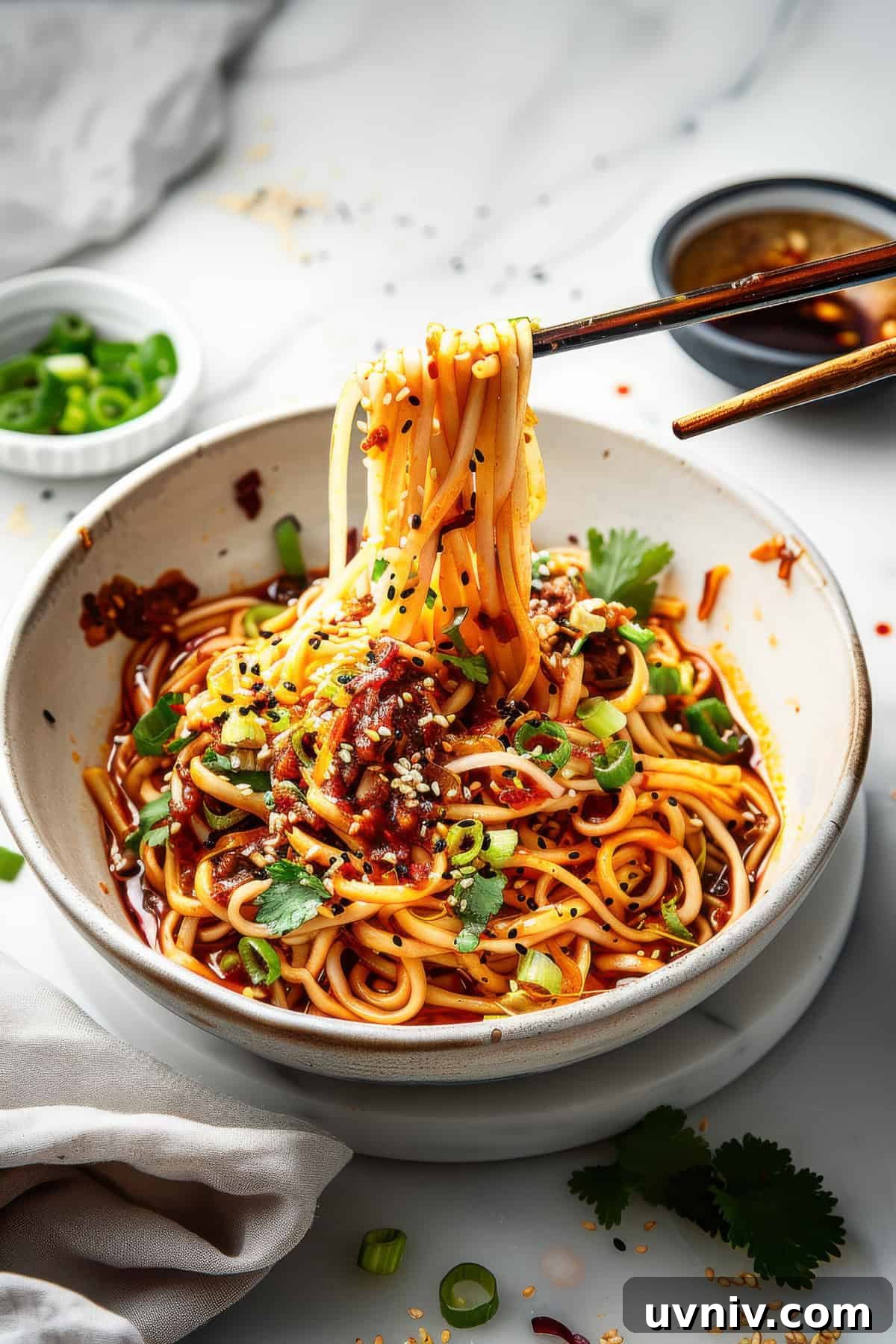 Szechuan noodles in a white bowl with green onions